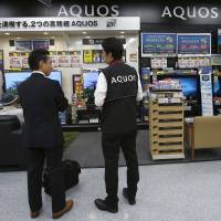 Shoppers look at Sharp Corp\'s Aquos television sets displayed at an electronics store in Tokyo. Residents and companies based in Yaita, Tochigi Prefecture, will be eligible for a grant when they purchase Sharp products. | REUTERS