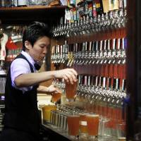 Beer necessities: A bartender pours glasses of craft beer at Bakusyu Club Popeye in Tokyo\'s Ryogoku neighborhood last weekend. | BLOOMBERG