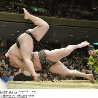 And down they go: Yokozuna Hakuho (bottom) falls en route to defeat against ozeki Goeido in the Summer Grand Sumo Tournament at Ryogoku Kokugikan on Thursday. | KYODO