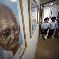 War and peace: A Japanese and an Indian student at an international school in Tokyo walk past a portrait of Mahatma Gandhi, who advocated nonviolent protest. Can those who haven\'t felt war follow his path? | AP