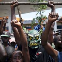 A protester wears a mask during a demonstration against President Pierre Nkurunziza\'s decision to run for a third term, in Bujumbura, Burundi, on Monday. East African leaders were to hold a summit in Tanzania on Wednesday aimed at breaking the political deadlock in Burundi and ensuring peaceful elections there, Tanzania\'s presidency said. | REUTERS