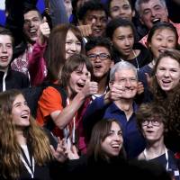 Apple CEO Tim Cook poses with scholarship winners following his keynote address at the Worldwide Developers Conference in San Francisco on Monday. | REUTERS