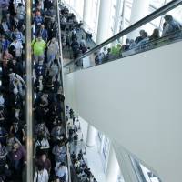 Apple Worldwide Developers Conference attendees ride escalators after a presentation in San Francisco on Monday. | AP