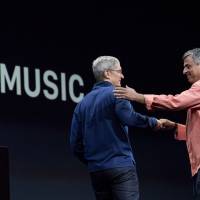 Eddy Cue (right), senior vice president of Internet Software and Services at Apple Inc.,  greets Tim Cook, chief executive officer of Apple Inc., on stage during the Apple World Wide Developers Conference (WWDC) in San Francisco on Monday. Apple Inc., the maker of iPhones and iPads, will introduce software improvements for its computer and mobile devices as well as reveal new updates, including the introduction of a revamped streaming music service. | BLOOMBERG