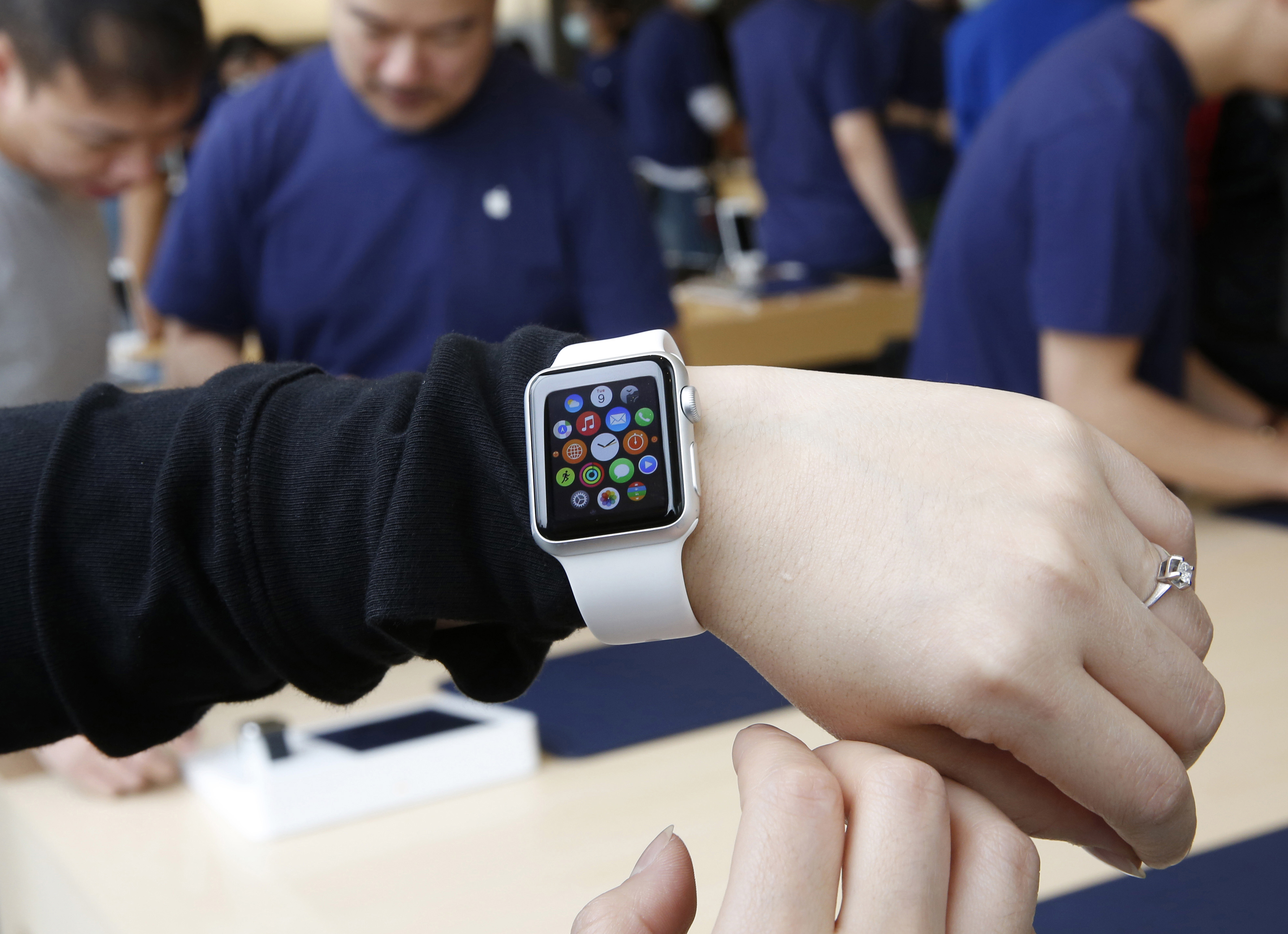 A customer tries on an Apple Watch at an Apple Store in Hong Kong  in April. Two months after Apple began taking online orders for its newest product, the company on Thursday said it will begin selling some models in its retail stores in two weeks. Apple also says it's cutting through a backlog of online orders, with most watches ordered by the end of May shipping within two weeks. | AP