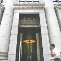 A man walks past Norinchukin Bank Ltd.\'s headquarters in Tokyo. The farmers\' lender with most of its money invested overseas says it sees little choice but to put additional funds into foreign assets this year. | BLOOMBERG NEWS