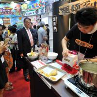 An employee of Megahouse Corp. demonstrates the Kiwamen Zukuri toy noodle machine at International Tokyo Toy Show 2015 on Thursday. The device, which can produce real ramen using readily available ingredients, will go on sale in late September. | YOSHIAKI MIURA