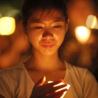 A woman holds a candle during a vigil at Victoria Park in Hong Kong on Thursday. | AP