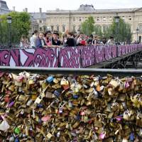 People stand on the Pont des Arts in Paris on Wednesday after padlocks were removed, though they remain on the bank. | AFP-JIJI