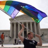 John Becker, 30, of Silver Spring, Maryland, waves a rainbow flag in support of gay marriage outside of the Supreme Court in Washington on Thursday. The same-sex marriage ruling was among those remaining to be released before the court\'s term ends this month. | AP