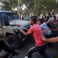 Israeli soldiers attempt to breakup a sit-in by Palestinians in the village of Kafr Malik, northeast of Ramallah on Sunday after clashes that resulted in the death of 21-year-old Palestinian Abdallah Ghanayem. An army spokesman told AFP that the Palestinian had died after he threw an incendiary device at a jeep and the vehicle overturned on him. Palestinian security sources said Israeli soldiers killed Ghanayem by hitting him with their jeep during clashes near Ramallah in the occupied West Bank. | AFP-JIJI