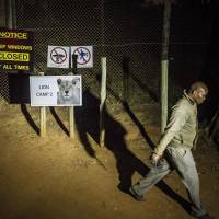 A man walks past warning signs at  Lion Park, near Johannesburg, Monday. A lion at the private wildlife park killed an American woman and injured a man driving through, an official said. The attack occurred when a lioness approached the passenger side of the vehicle as the woman took photos and then lunged, said Scott Simpson, assistant operations manager at Lion Park. | AP