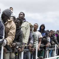 Migrants wait to disembark from the Italian Coast Guard ship Peluso, on the tiny Italian island of Lampedusa, Sunday. Around 75,000 migrants have been picked up trying to enter Italy and Greece from Libya so far this year. More than 1,800 are feared to have died. Most rescue emergencies happen some 40 nautical miles from Libya. | AP