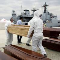 Staff carry a coffin Sunday in the Sicilian harbor of Augusta. The corpses of 17 migrants were brought ashore in Sicily aboard an Italian naval vessel on Sunday along with 454 survivors as efforts intensified to rescue people fleeing war and poverty in Africa and the Middle East. | REUTERS