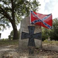A Confederate battle flag flies at the grave of Lewis Frederick Sweat, a soldier in the Confederate States Army in the U.S. Civil War, in Boone Hill Cemetery in Summerville, South Carolina, on Tuesday. | REUTERS