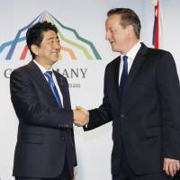Prime Minister Shinzo Abe and British leader David Cameron shake hands for the cameras before holding bilateral talks Monday on the sidelines of the Group of Seven summit in Schloss Elmau, Germany. | KYODO