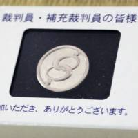 A token badge given to people who have served as lay judges is shown, with a message on the box saying \"Thank you.\" | KYODO
