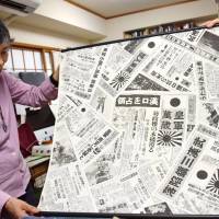 Chizuko Morita, head of a group holding an exhibition of furoshiki wrapping cloth used during World War II, shows a cloth printed with newspaper articles. | KYODO