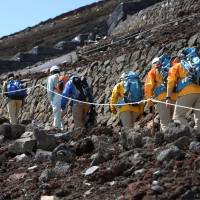 Yamanashi prefectural officials and climbing guides check the Yoshida trail on Mount Fuji on Thursday, before the route officially opens next Wednesday. | KYODO