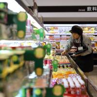 A store worker checks products at an Aeon Co. supermarket in Tokyo in 2013. Products bearing new explanatory food labels will hit stores nationwide this week. | BLOOMBERG