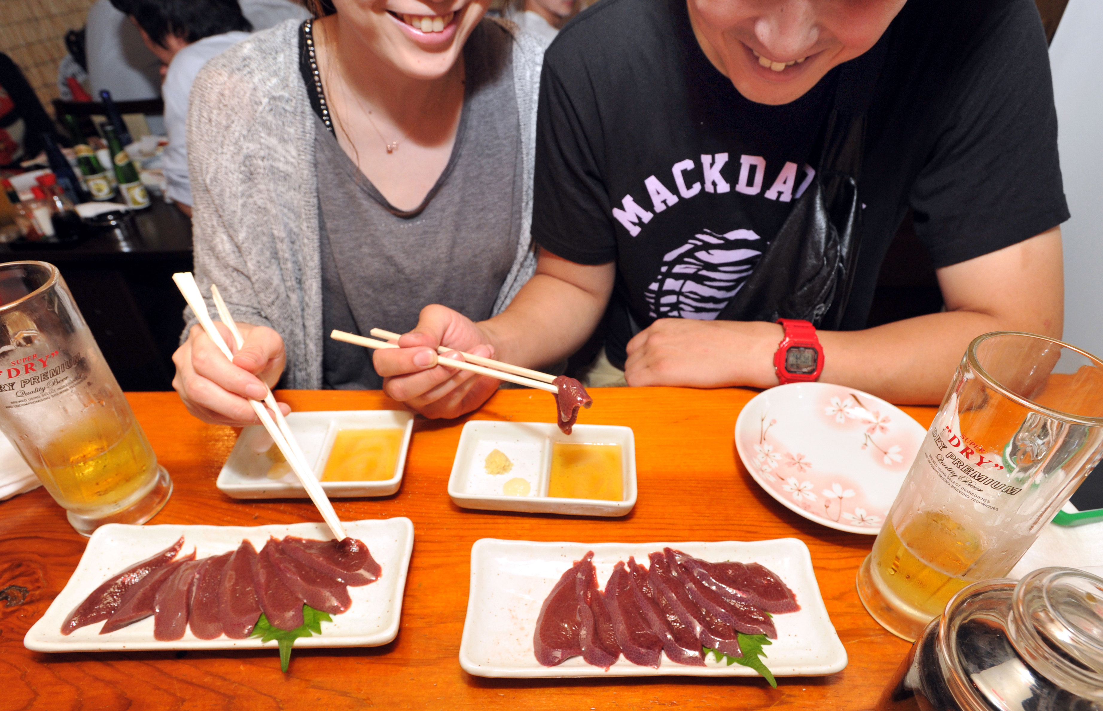 Customers at Aji no Isohei, a traditional Japanese pub in Tokyo's Oimachi district, eat raw pork liver Thursday evening before a new regulation banning it took effect the following day.  | YOSHIAKI MIURA