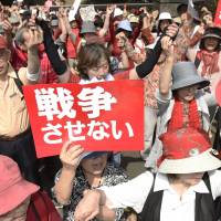 Demonstrators brandish anti-war signs Saturday outside the Diet building in Tokyo, in protest at the government\'s security bills that would expand the scope of overseas operations by the Self-Defense Forces. | KYODO