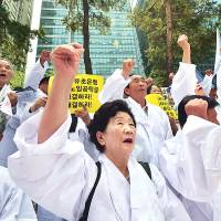 South Korean family members of victims of World War II chant slogans outside the Japanese Embassy in Seoul on Monday during an anti-Japan rally. | AFP-JIJI