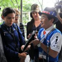 Volunteer guide Norio Hasegawa talks Friday with tourists from Colombia in Tokyo\'s Shinjuku district. | SATOKO KAWASAKI