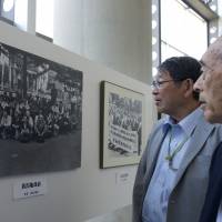 Sakae Kanda (right) and Eiichi Minagawa look at a photo of Niigata Minamata victims outside a court prior to a commemorative event in Niigata on May 31. | ROB GILHOOLY
