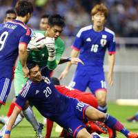 Singapore goalkeeper Izwan Mahbud denies Japan defender Tomoaki Makino during their World Cup qualifier in Saitama last Tuesday. | AP