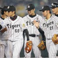 The Hanshin Tigers congratulate each other after an 11-4 drubbing of the Hokkaido Nippon Ham Fighters on Tuesday at Koshien Stadium. | KYODO