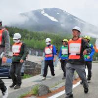 Tourism workers and emergency personnel carry out an evacuation drill on the slopes of Mount Fuji on Thursday, practicing how to take tourists to safety if the iconic volcano erupts. The Yamanashi Prefectural Government has for the first time drawn up an evacuation map for hikers, which outlines different routes depending on which vents blow. | KYODO