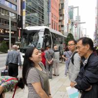 Chinese tourists chat in the Ginza shopping district in central Tokyo. The recent surge in Chinese visitors to Japan is sparking a boom in demand for tour buses. | KYODO