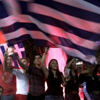 \"No\" supporters wave Greek flags by the parliament in Athens on Sunday after citizes voted overwhelmingly \"No\" on a historic bailout referendum. | REUTERS