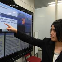 A Hitachi engineer points to a computer display during a presentation of software it says returns intelligent answers to questions, at its Tokyo headquarters on Wednesday. | AFP-JIJI
