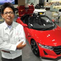 Ryo Mukumoto, the youngest ever manager to oversee the development of a new Honda Motor Co. car, poses with the S660 sports car, at Honda headquarters in Tokyo in May. | YOSHIAKI MIURA