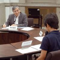 Bank of Japan Gov. Haruhiko Kuroda listens to a junior high school boy during a summer seminar for kids hosted by the central bank Tuesday in Tokyo. | KYODO