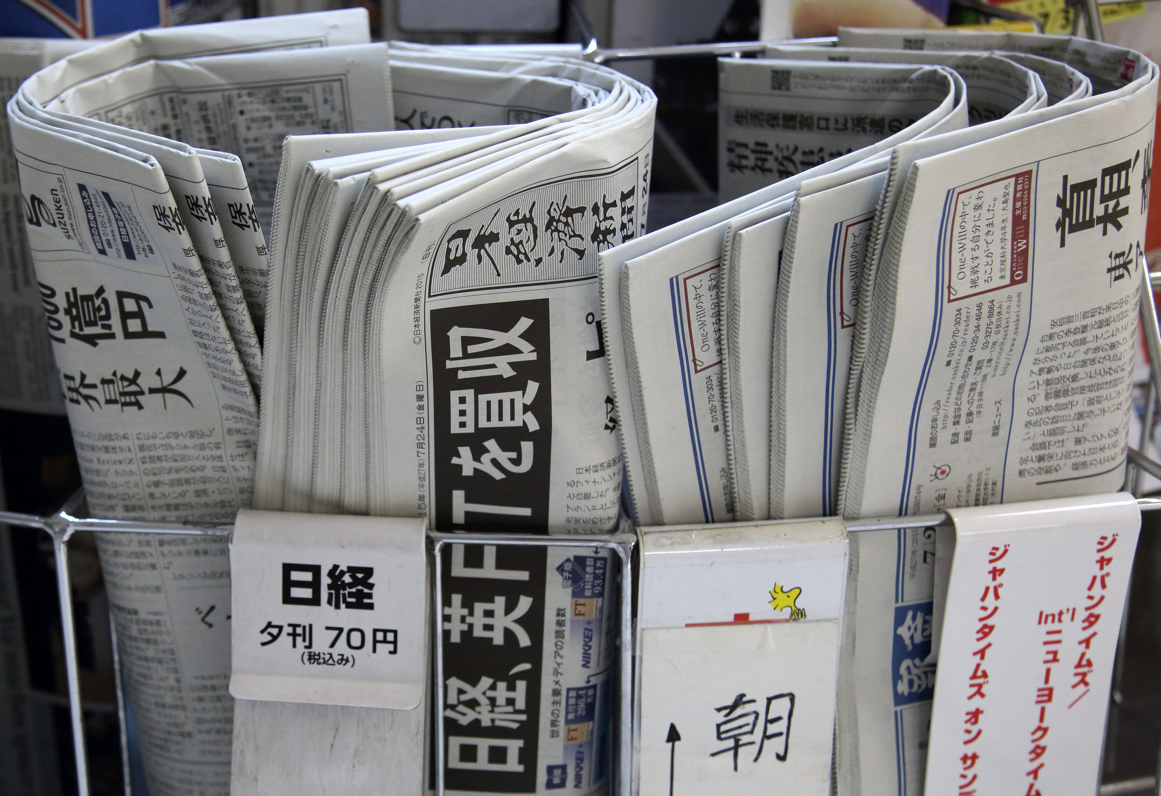 Newspapers, including the Nikkei (center), are displayed for sale in Tokyo on Friday. The headline set in black says 'Nikkei buys British FT.' | BLOOMBERG