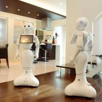Pepper robots run through their paces at a Yamada Wood House Co. showroom in Osaka on Friday. | KYODO