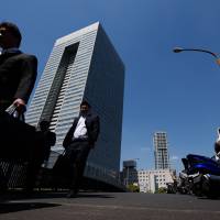 Pedestrians walk past Toshiba Corp.\'s Tokyo headquarters in May. | BLOOMBERG