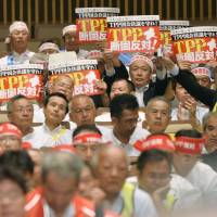 Japanese farmers hold up placards as they take part in a rally opposing the Trans-Pacific Partnership initiative in Tokyo on Monday. The event was held one day before trade ministers from the 12 Pacific Rim nations resumed talks on the deal in Hawaii. | KYODO