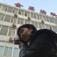 In this March 2014 image, Wang Yu, a lawyer representing human rights activist Cao Shunli, can be seen talking on the phone in front of a Beijing hospital where Cao was being treated in intensive care. Wang had been barred from visiting Cao. | REUTERS