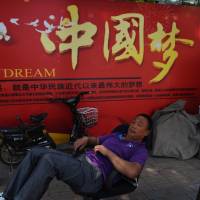 A man rests in front of a banner about the \"China Dream,\" President Xi Jinping\'s vision for the nation\'s future, in Beijing on Tuesday. | AFP-JIJI