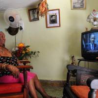 A woman in Havana watches U.S. President Barack Obama talking on TV about the re-establishment of full diplomatic ties with Cuba. | AFP-JIJI