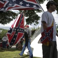 Confederate battle flags are flown during a Confederate Medal of Honor ceremony for Sgt. Tapley Mays in Pearisburg, Virginia, on Saturday. Mays, an ensign in Company D of the 7th Virginia, was killed in battle carrying the Confederate battle flag. \"The flag isn\'t a racist symbol. It\'s a symbol of an oppressive government,\" said Patrick Seay, 16 (right). Supporters of the flag turned out en masse Sunday in Ocala, Florida, in a vehicle parade. | JOHN ROARK / THE ROANOKE TIMES VIA AP