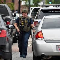 An ATF officer patrols near the scene of an unconfirmed shooting at the Navy Yard in Washington, D.C. on Thursday. The Navy Yard was put on lockdown Thursday amid unconfirmed reports of an active gunman on the military facility, the scene of a deadly shooting two years ago. | AFP-JIJI