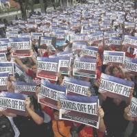 Activists hold up signs that read, \"Hands off PH!\" &#8212; the Philippines &#8212; during a demonstration against China\'s claims to areas in the South China Sea that Manila considers its own outside the Chinese Consulate in Manila\'s Makati City on June 12. | REUTERS