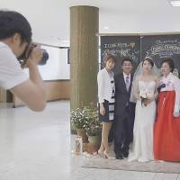 A bride poses for photographs with her family before a ceremony at a budget wedding hall at the National Library of Korea in Seoul on May 16. | REUTERS