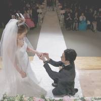 A groom puts a wedding ring on his bride\'s finger during a ceremony at a budget wedding hall at the National Library of Korea in Seoul on May 16. | REUTERS