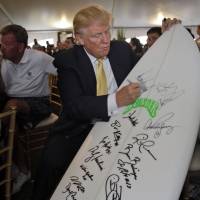 Republican presidential candidate Donald Trump signs a surf board as part of a fundraiser in the Bronx borough of New York, Monday. | AP